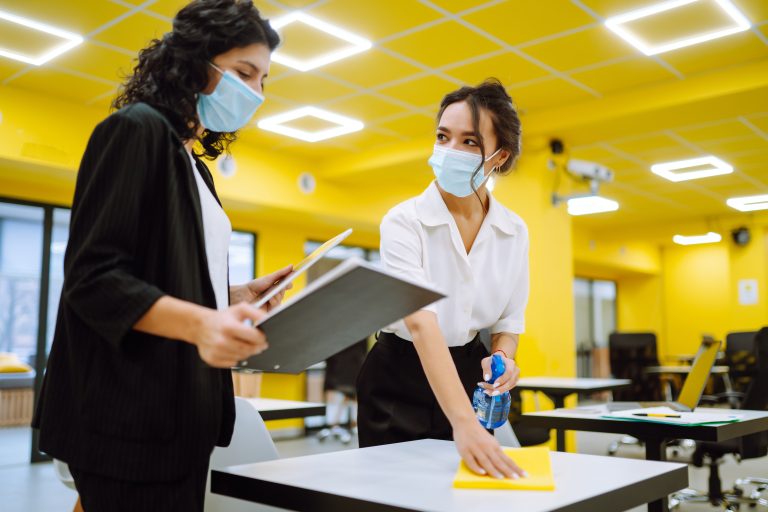 Cleaning and disinfection of the desktop. Man in protective sterile mask cleans the working desk.