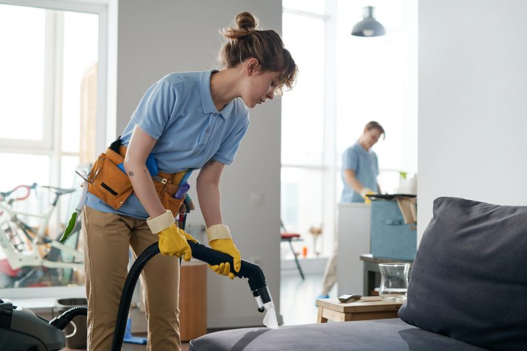 Cleaning service workers working in apartment in team, they vacuuming furniture and cleaning the room